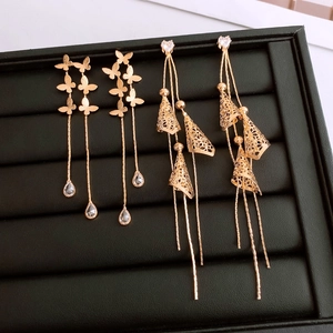Detailed macro of 18K gold plated heart and butterfly tassel earrings on a display tray