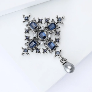 Detail view of baroque silver cross brooch with blue crystals and grey pearl pendant