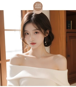 Elegant long tassel pearl earrings with gold chain on model in warm indoor light