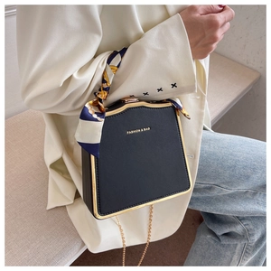 Fashionable black leather box bag with silk scarf handle detail worn by model