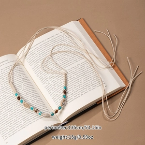 Detail of bohemian woven waist rope with turquoise beads and natural shells on vintage book