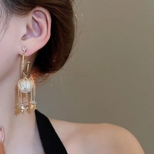 Detailed close-up of golden tassel earrings with pearls and zircon star moon pendants
