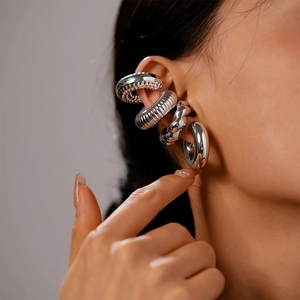 Macro detail of four silver metal ear cuffs featuring twisted, beaded, and smooth textures