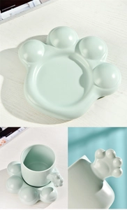 Detail of light green ceramic coffee mug featuring a 3D cat paw handle and saucer