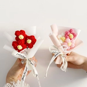 Mini hand-knitted flower bouquets with persimmon and sunflower in elegant white wrapping
