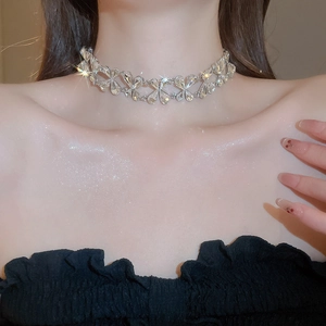 Close-up of sparkling crystal choker necklace featuring intricate bow-shaped links on model