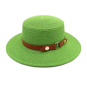Close-up of fruit green straw boater hat with brown leather band and gold rivets
