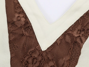 Detail view of brown lace stitching with beige woven trim on the V-neckline