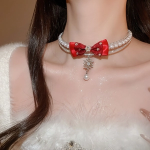 Detail of elegant pearl necklace with red bow and snowflake pendant on model