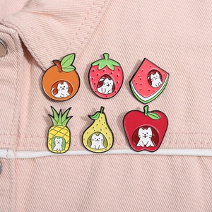 Detail view of six cute cat and fruit enamel pins pinned on pink denim fabric material