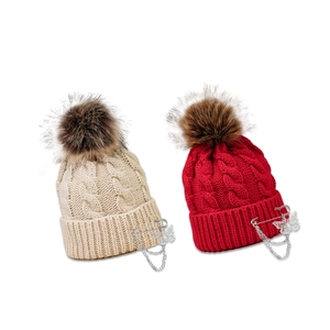 Chunky knit beanie with butterfly pin and faux fur pompom in cream and red colors