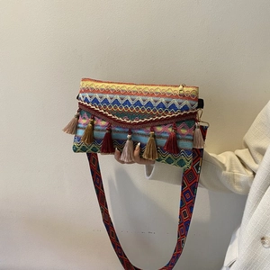 Detail of bohemian woven crossbody bag with colorful tassels and geometric strap