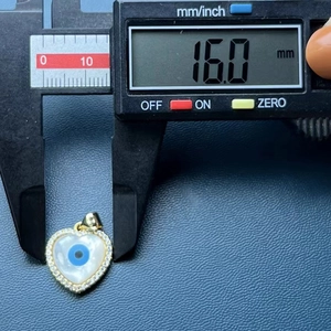 Macro shot of a 16mm heart-shaped evil eye shell pendant measured with a digital caliper