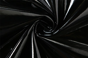 Détail macro du tissu verni noir brillant avec plis en spirale et reflets de lumière