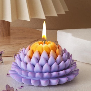 Gradient lotus flower scented candle with burning wick on an elegant wooden base
