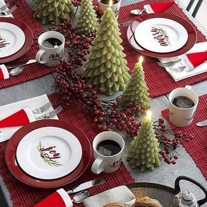Christmas table setting with green tree candles, red berry wreaths, and mini Santa hats