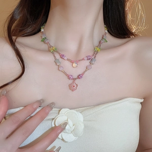 Detailed view of a double-layered beaded necklace with flower and teardrop pendants
