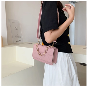 Pink quilted crossbody bag with decorative chain and wide strap on model