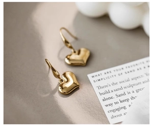 Macro shot of polished gold-finished vintage 3D heart-shaped drop earrings
