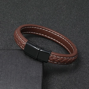 Detail of brown braided leather bracelet with white stitching and black magnetic clasp