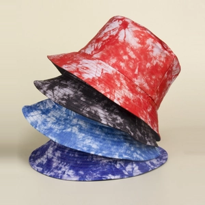 Vue détaillée de quatre bobs tie-dye multicolores empilés sur un fond de ton neutre