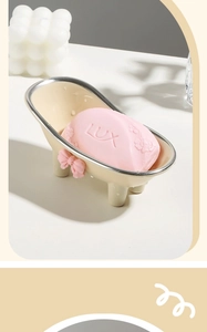Detail of bathtub soap dish with pink bow and silver trim on white tabletop