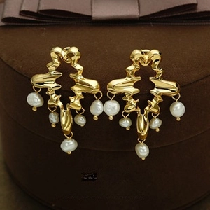 Detail of luxury gold earrings with baroque pearls on a velvet jewelry box