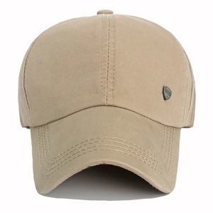 Detail of khaki cotton baseball cap showing side metal shield badge and stitched curved brim