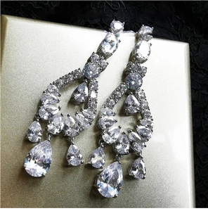 Macro shot of silver drop earrings with zircons on a gold case and black lace