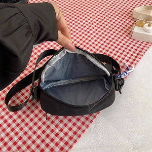 Close-up of the interior zipper pocket and grey lining of the black nylon crossbody bag