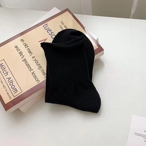 Close-up of black cotton crew socks with ribbed cuffs folded on a vintage book