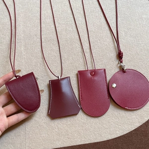 Faux leather magnetic glasses holder necklace with red charms on a beige fabric background