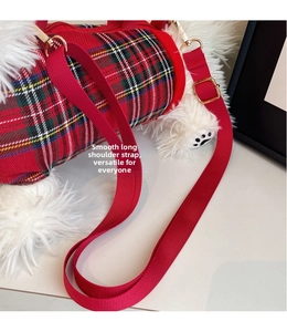 Detail of red tartan cylinder crossbody bag with adjustable nylon strap and gold hardware