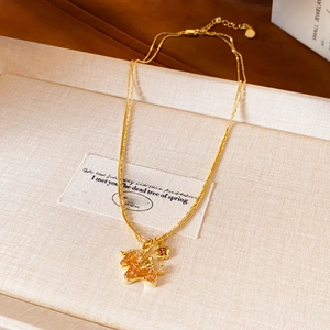 Detail of double-layer gold horse necklace with amber crystal and flower charm
