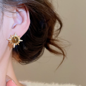 Close-up of model wearing sunburst 18K gold earrings with tiger eye and zircons