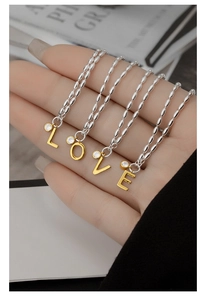Close-up of S925 silver chains with gold LOVE letter pendants and zircon stones