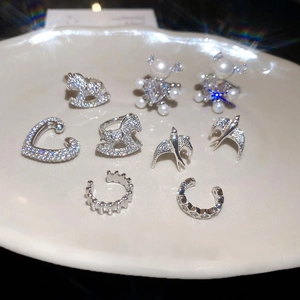 Detailed view of elegant silver ear cuffs set with zircon and pearls on ceramic tray