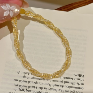 Macro shot of gold twisted rope bracelet featuring high-shine texture and zircon details