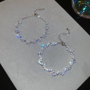 Detail of silver butterfly zircon and pearl bracelets on a gray textured surface