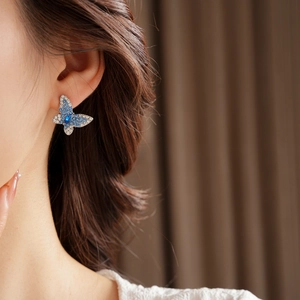 Detalle de pendiente de mariposa con piedra marquesa azul y cristales pavé brillantes