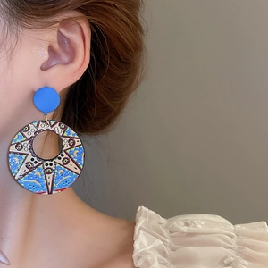 Artistic blue floral patterned large hoop earring shown on a model in a close-up profile view