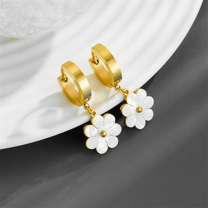 Gold hoop earrings with white flower charms and center beads on a minimalist white tray