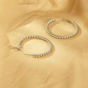 Detailed view of silver twisted hoop earrings on luxurious golden satin background
