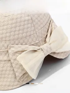 Close-up of beige sun hat featuring unique embossed texture and elegant chiffon bow