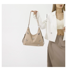 Detail of beige nylon shoulder bag with silver butterfly accents and matching strap