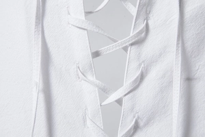 Detail van de vetersluiting en katoen-linnen textuur op het witte Henley-shirt