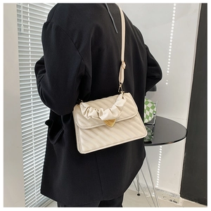Detail of cream crossbody bag with heart clasp and pleated handle worn by model