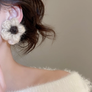 Close-up of knit flower earring with pearl drop on model showing soft plush texture