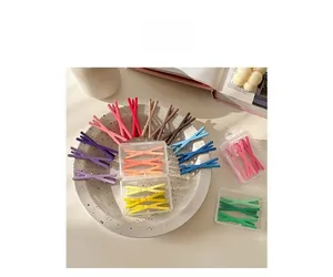 Colorful matte X-shaped hair clips in various pastel tones inside a decorative ceramic dish