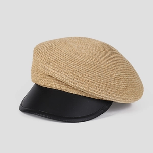Detail of woven straw body and black leather brim on a stylish newsboy cap